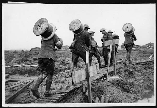IWM Q 6050 Battle of Poelcappelle. Royal Engineers taking drums of telephone wire along a duckboard path up to the front between Pilckem and Langemarck, 10 October 1917.