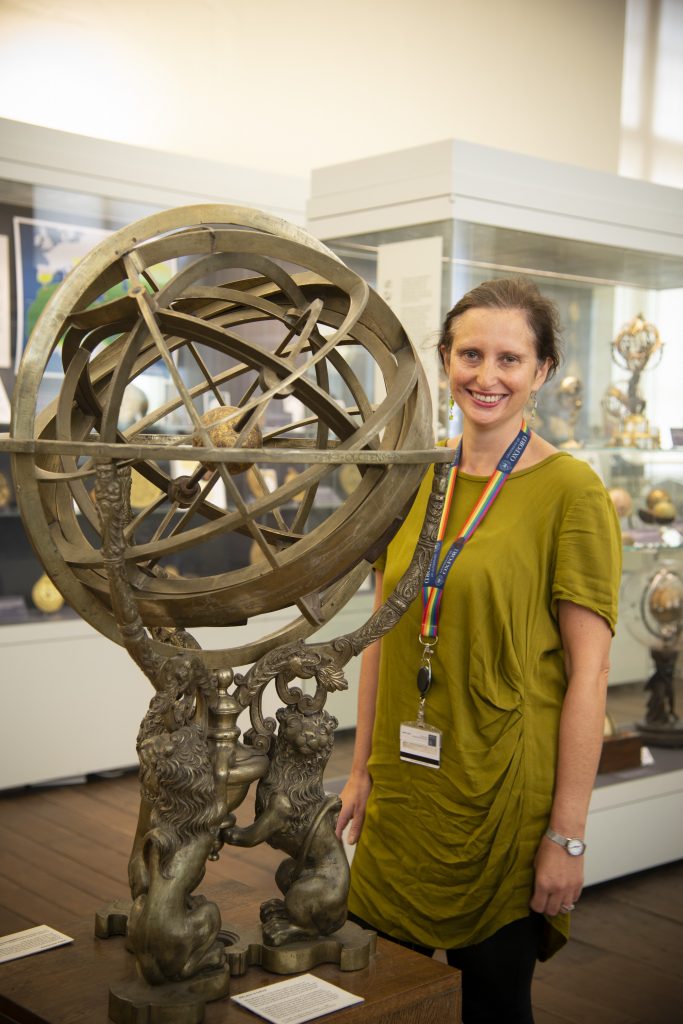 Helen Pooley standing behind the armillary sphere - an interlocking set of rings balancing on top of three lions. The armillary sphere is the same height as Helen.