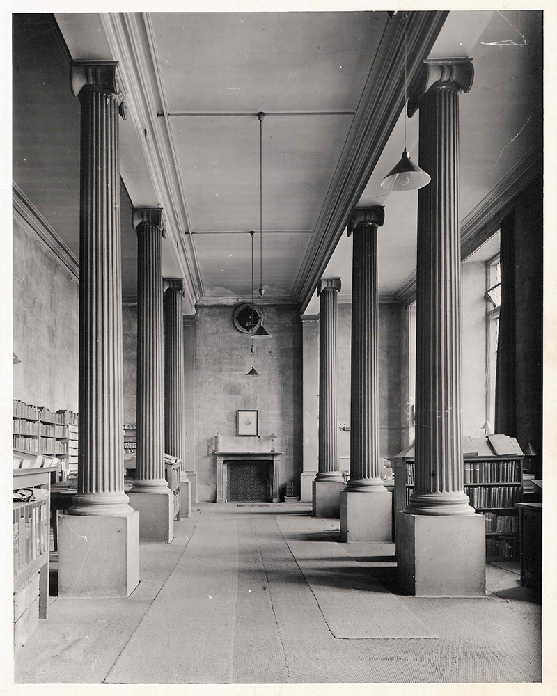 the main floor of the building, it is mostly empty with desks running down the right side of the room and shelves on the left.]